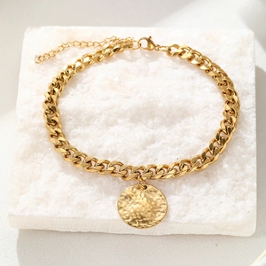 Gold stainless steel Cuban anklet with hammered disc pendant on white stone podium