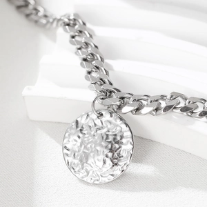 Polished silver stainless steel Cuban link anklet with a hammered round metal pendant charm