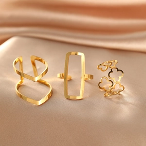 Detailed view of three gold geometric hollow-out open rings on champagne silk fabric