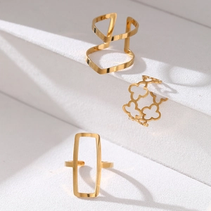 Detailed view of three gold geometric rings featuring hollow clover and rectangular shapes