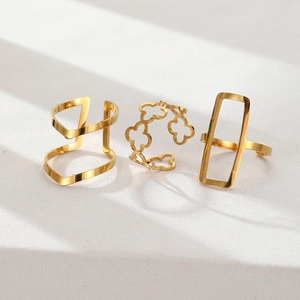 Detailed view of three gold geometric hollow rings on a textured white stone surface