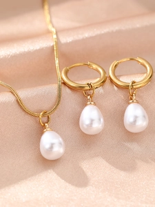 Detail of freshwater pearl necklace and gold hoop earrings on luxury champagne silk
