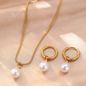 Elegant gold snake chain necklace and hoop earrings set with teardrop pearls on silk