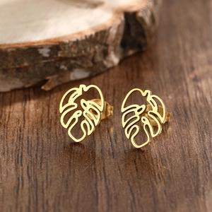 Boucles d'oreilles feuilles de monstera dorées en acier inoxydable ajouré sur bois rustique