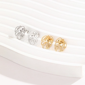 Détail de boucles d'oreilles feuille de monstera découpées au laser, or et argent