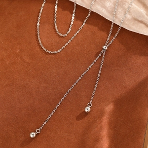 Minimalist Y-shaped stainless steel necklace with round silver beads on a satin background