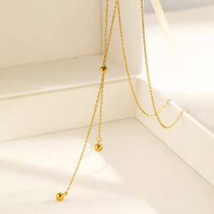 Detailed view of gold tassel necklace with polished beads in a premium jewelry box