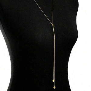 Detail of a 18K gold-plated Y-shaped tassel necklace featuring polished metallic beads