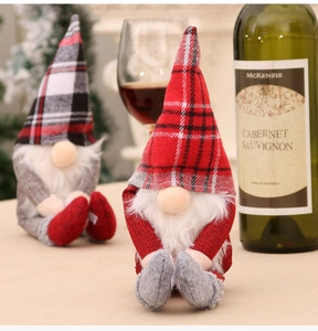 Detail von zwei handgefertigten Weihnachtswichteln mit karierten Hüten neben Weinflasche