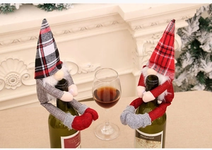 Weinflaschenhüllen im Weihnachtswichtel-Design mit Karomuster auf einem Kaminsims