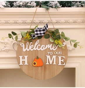 Close-up of wooden welcome sign featuring pumpkin motif and black-white plaid ribbon