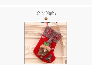 Detailed view of red Christmas stocking with 3D Santa and grey plaid trim hanging on mantel