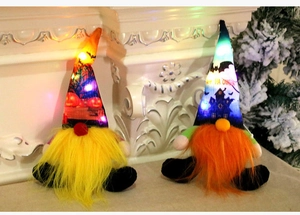 Close-up of two glowing Halloween gnomes with pumpkin and castle prints on a fireplace