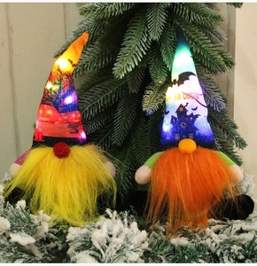 Detail of LED glowing Halloween gnomes with pumpkin hats in a snowy pine forest