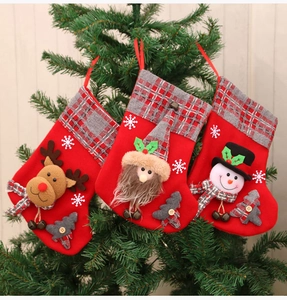 Hanging Christmas stockings with plush reindeer, Santa, and snowman on a tree branch