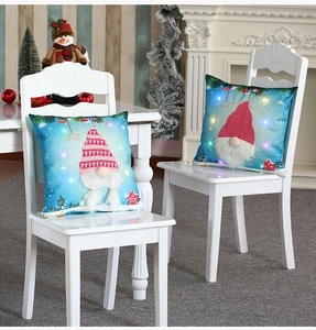 Close-up of LED glowing Christmas gnome pillow cover on a white chair for home decor