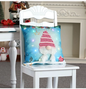 Close-up of lighted Christmas gnome pillow cover with plush beard on white chair