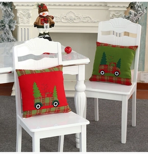 Detail of red and green Christmas pillow covers with truck and tree on a white chair