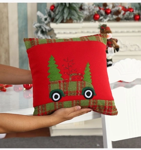 Close-up of festive red velvet pillowcase with embroidered truck and Christmas trees