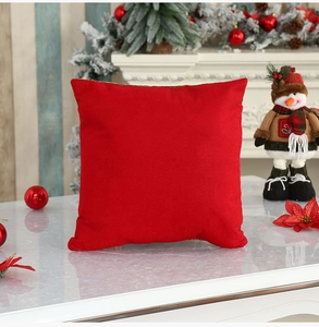 Close-up of red velvet Christmas pillow cover on a marble surface with holiday decor