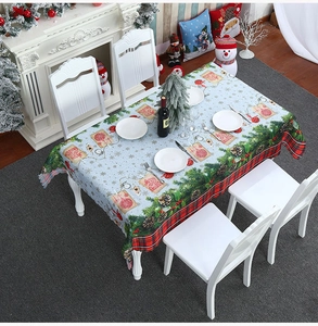 Detail of light blue Christmas tablecloth with red plaid edges and festive pine motifs