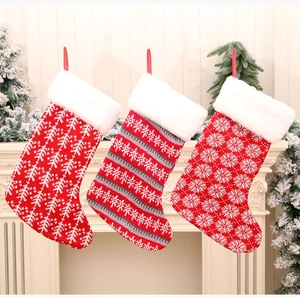 Drie gebreide kerstsokken met pluche rand hangend aan een witte feestelijke open haard