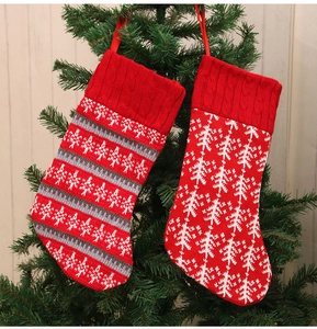 Detail view of knitted red Christmas stockings with snowflake patterns hanging on a tree