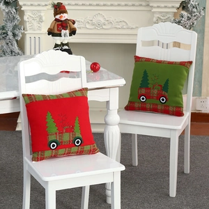 Christmas cushion covers with embroidered trucks and plaid borders on white chairs