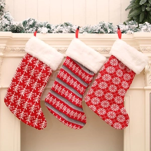 Drie rood-witte gebreide kerstsokken met pluche boord aan een feestelijke schoorsteenmantel