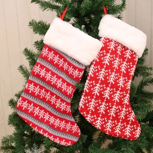 Gebreide kerstsokken met witte rand van kunstbont en feestelijke patronen aan de boom