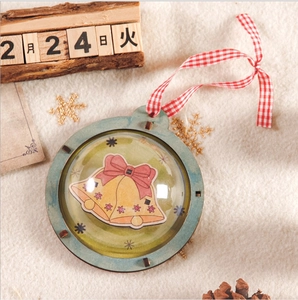 Detail of DIY Christmas wooden ornament with red plaid string and 3D dome showing bells