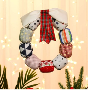 Detail of a Christmas cloth wreath with red and green plaid patterns and a white silk bow
