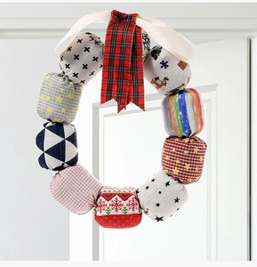 Close-up of a handmade Christmas fabric wreath with plaid bow and festive patterns