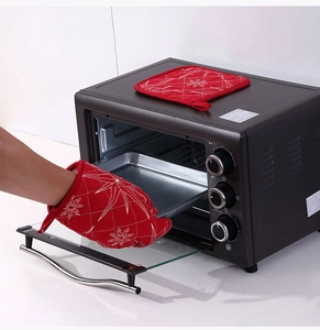 Quilted red heat-resistant oven mitt and pot holder set used for a hot baking tray