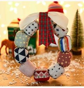 Close-up of handmade Christmas fabric wreath featuring festive patterns and cream satin bow