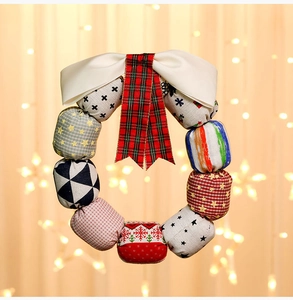 Close-up of handmade fabric Christmas wreath with colorful patterns and satin bow detail