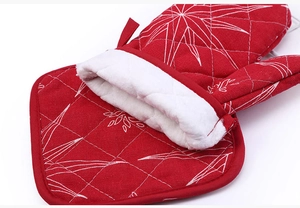 Macro view of red quilted oven mitt with white snowflake embroidery and soft fleece lining