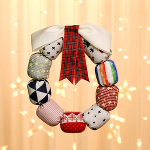 Christmas fabric wreath with colorful patterns and a large white satin bow for door decoration