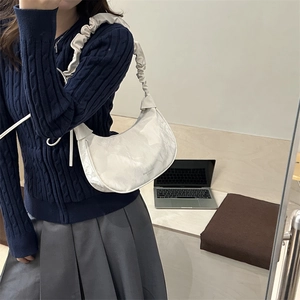 Sac hobo blanc avec bandoulière plissée et texture nuage lors d'un selfie lifestyle