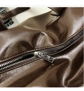 Close-up of smooth silver metal zipper and dark brown glossy leather on bag