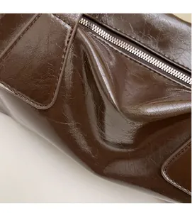 Detailed macro view of dark brown oil-wax leather texture and metal zipper hardware