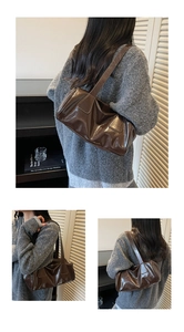 Detail of dark brown glossy shoulder bag with pleated texture on the leather surface