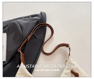 Détail de la bandoulière réglable en cuir marron et de la fermeture éclair du sac en toile