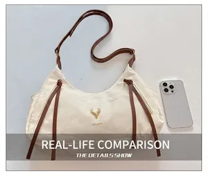 Détail du sac Hobo blanc avec logo cerf doré et bandoulière réglable en cuir marron