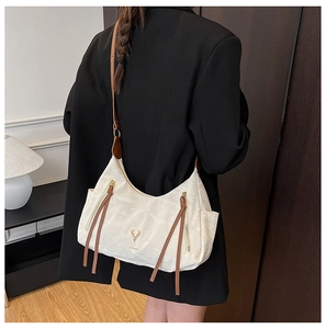 Détails du sac à bandoulière beige avec lanières marron et logo élan en métal doré