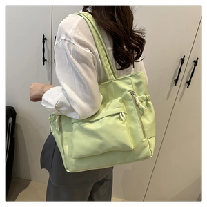 Close-up of light green nylon tote bag with drawstring detail and large front pocket