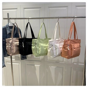 Row of colorful oxford tote bags with multiple pockets hanging against a white door