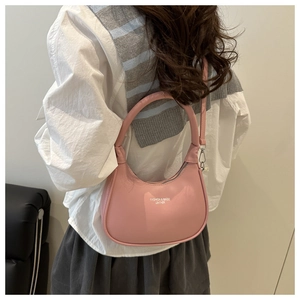 Detail of pink crescent moon leather handbag featuring top handle and brand logo print