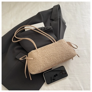 Vista piatta di una borsa a spalla beige in ecopelliccia con fiocchi decorativi laterali
