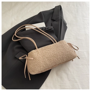 Gros plan sur le sac bandoulière en peau de mouton beige avec nœuds décoratifs